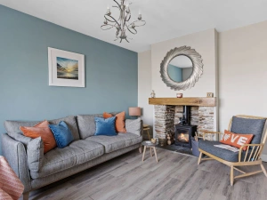 Living room with cosy log burner, sofa and arm chair - Bumble Cottage