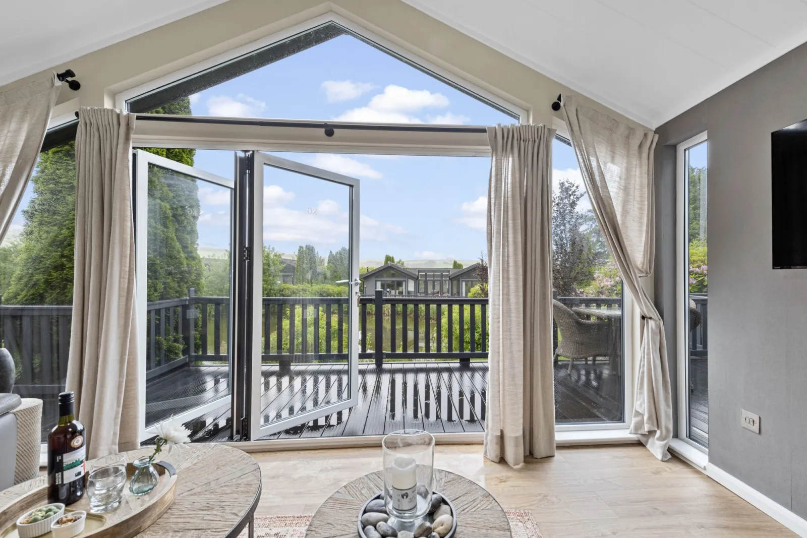 Living area with TV, sofa, doors leading to decking - Brayford Lodge, Kentisbury Grange