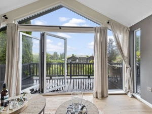Living area with TV, sofa, doors leading to decking - Brayford Lodge, Kentisbury Grange