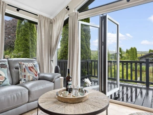 Sofa within lounge, bifold doors leading to decking area and coffee table - Brayford Lodge, Kentisbury Grange