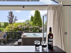 Kitchen leading to decking with hot tub and seating area - Brayford Lodge, Kentisbury Grange