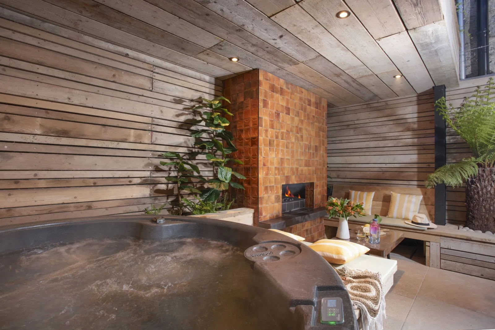 undercover hot tub, fireplace and seating within garden - Sandy Boobies