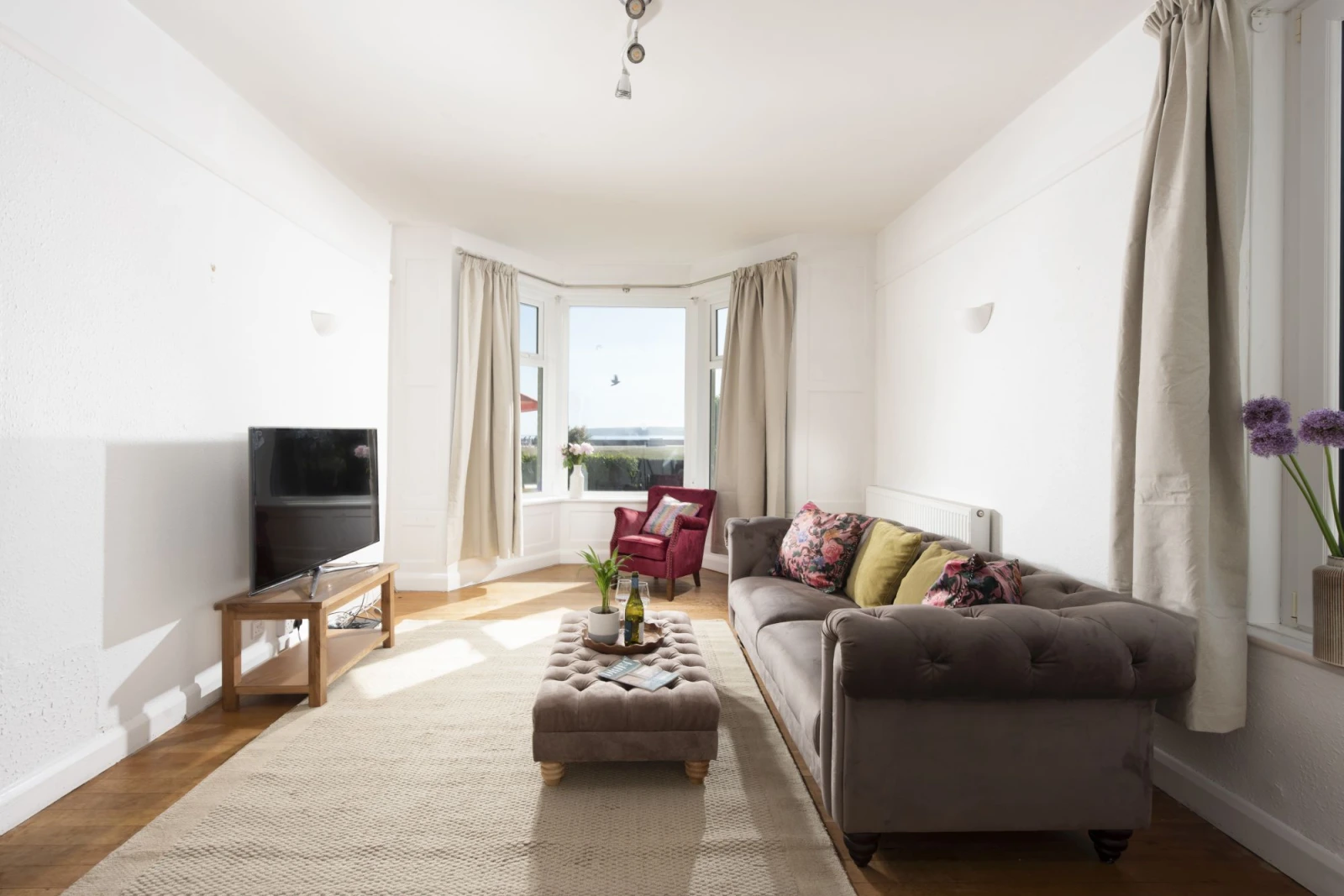 Lounge with coffee table, sofa, armchair, bay window looing out to garden and sea view - Folneth