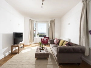 Lounge with coffee table, sofa, armchair, bay window looing out to garden and sea view - Folneth