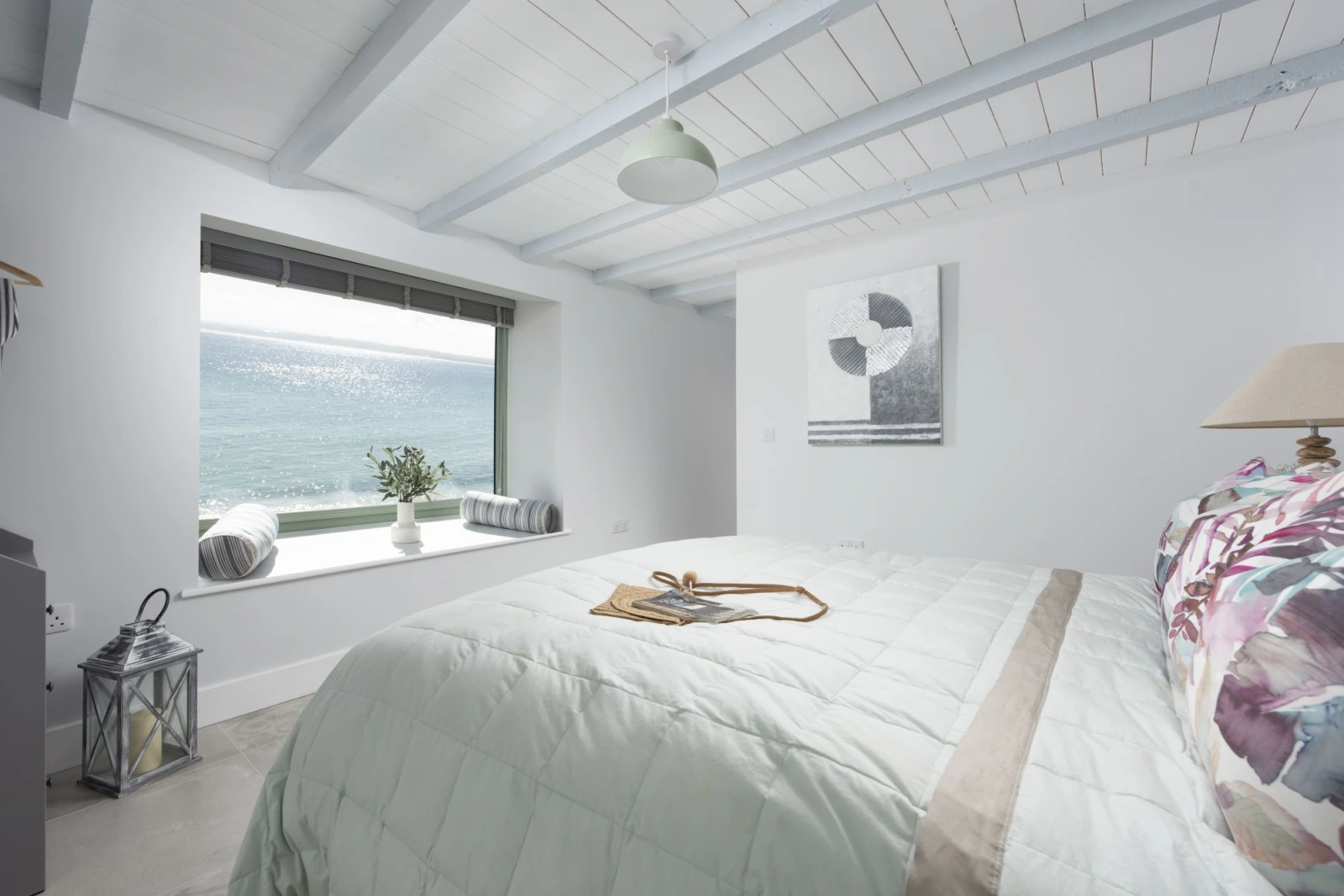 Large window with ocean view from bedroom, side table, lamps, towels  - Mermaids