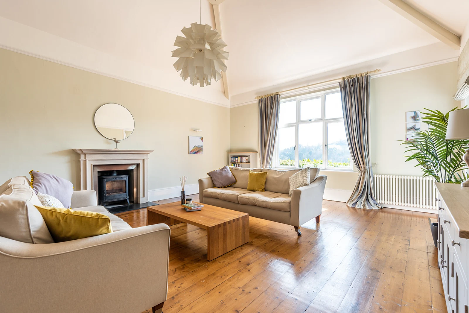 Elegant sitting room with high ceilings, exposed oak flooring and feature log burner.