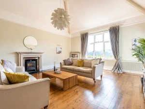Elegant sitting room with high ceilings, exposed oak flooring and feature log burner.