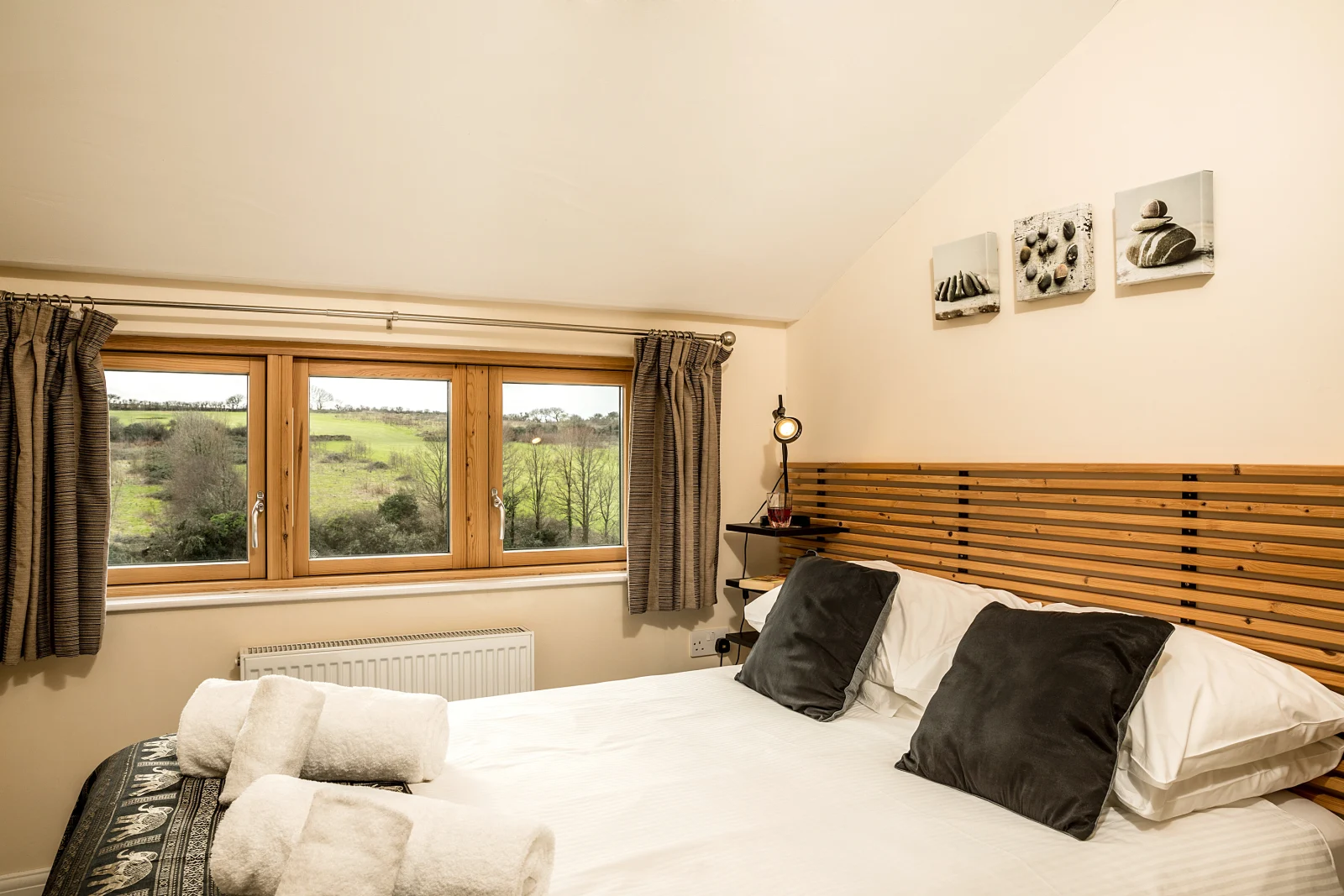 The bijou, second bedroom has a double bed and a chest of drawers. You can see the views across the fields and the edge of the golf course.