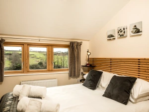 The bijou, second bedroom has a double bed and a chest of drawers. You can see the views across the fields and the edge of the golf course.