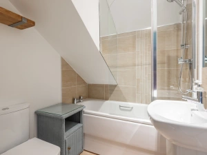 The bathroom with bath and over head shower
