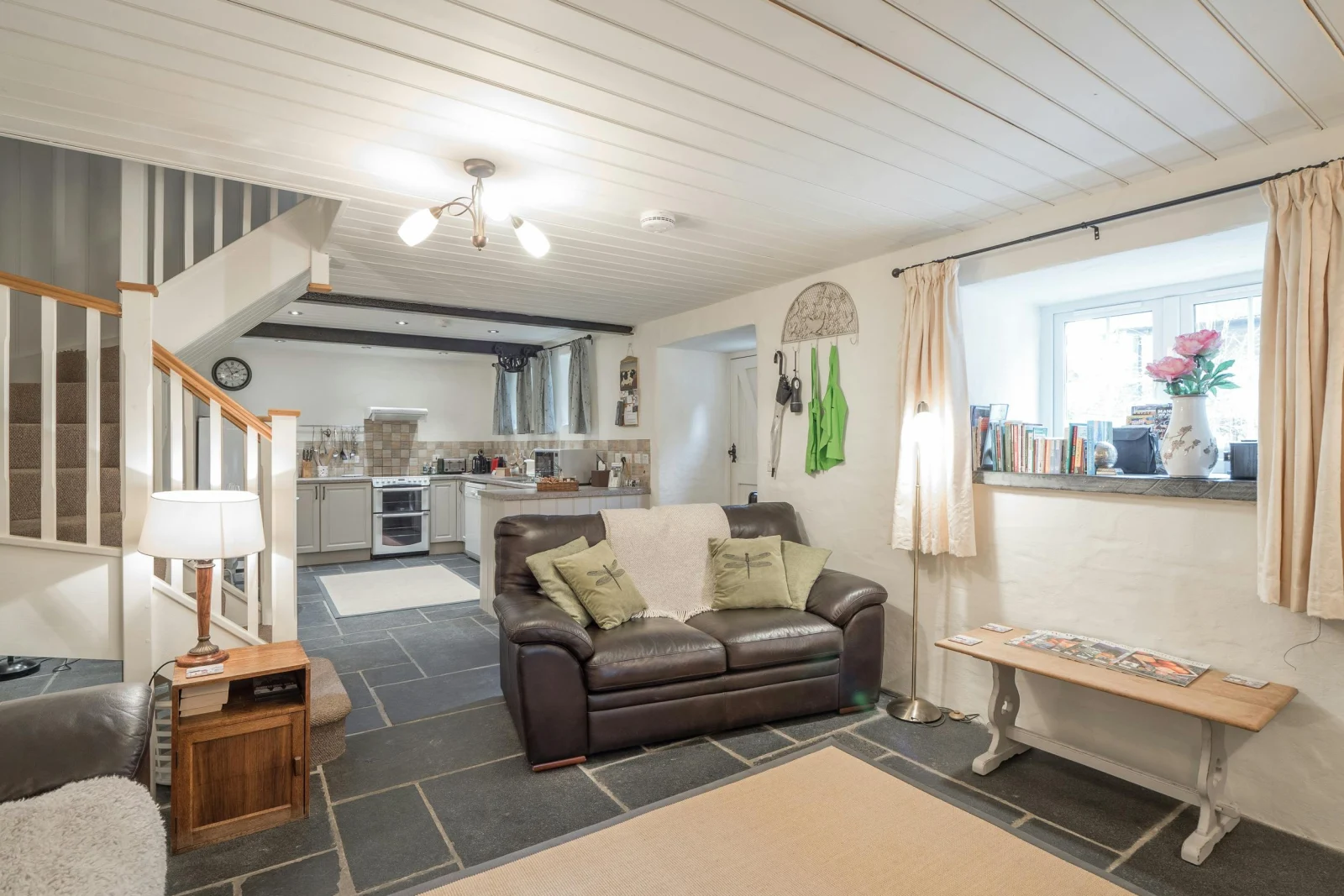 Living area and kitchen, stairs to first floor: sofa, low table, floor lamp, small unit with lamp