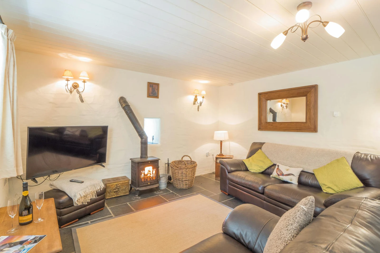 Sofas, stool, corner unit with lamp, large wall mounted mirror, wood burner and TV
