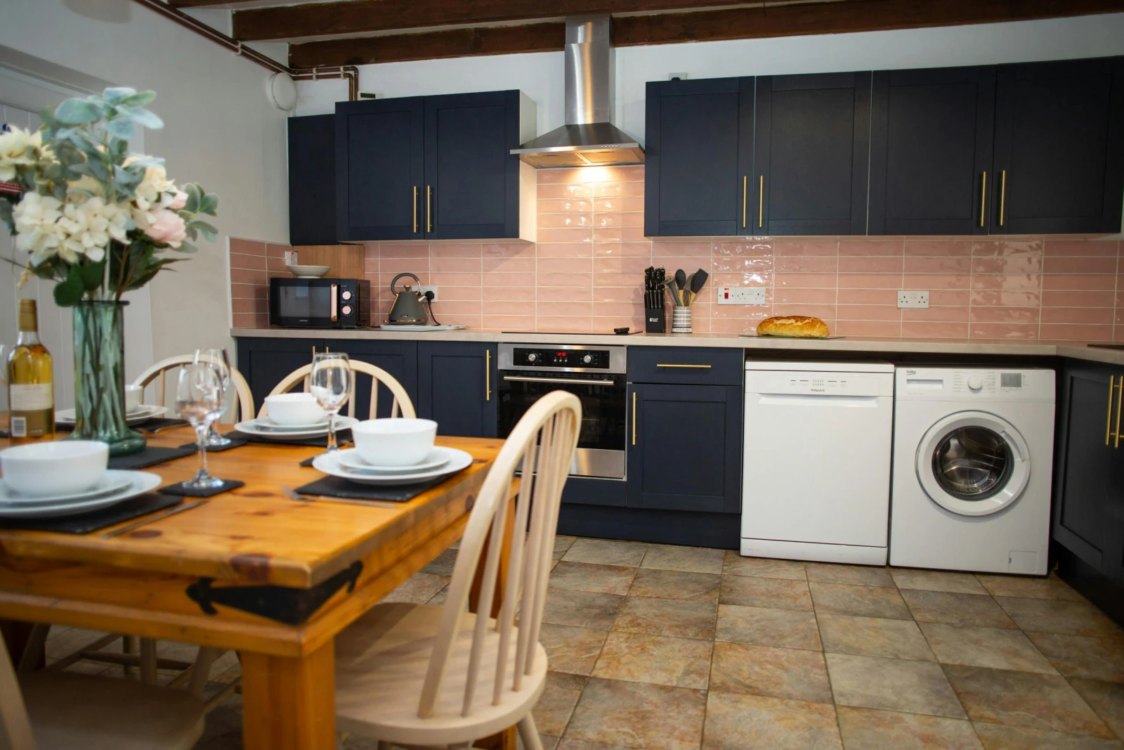 Fitted kitchen with washing machine, dishwasher, oven and hob, microwave, kettle, dining table and chairs