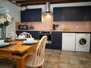 Fitted kitchen with washing machine, dishwasher, oven and hob, microwave, kettle, dining table and chairs