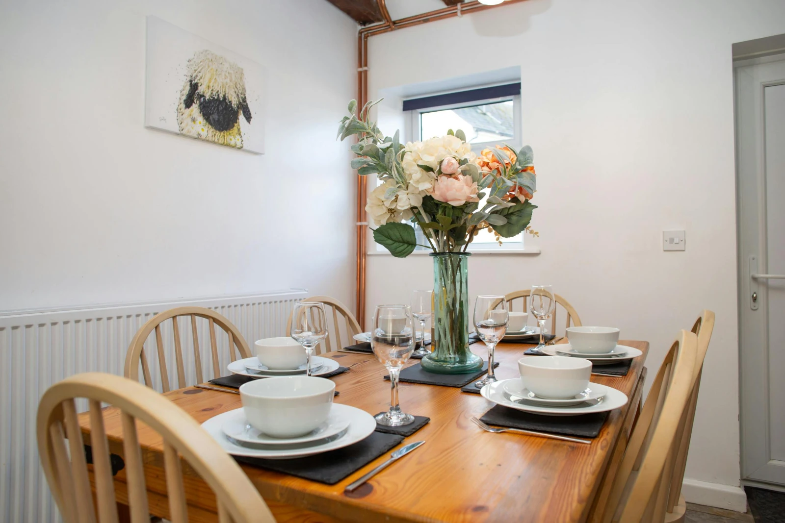 Dining table with six chairs laid for dinner