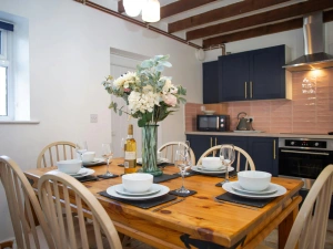 Kitchen/diner with microwave, kettle, oven and dining table with six chairs laid for dinner