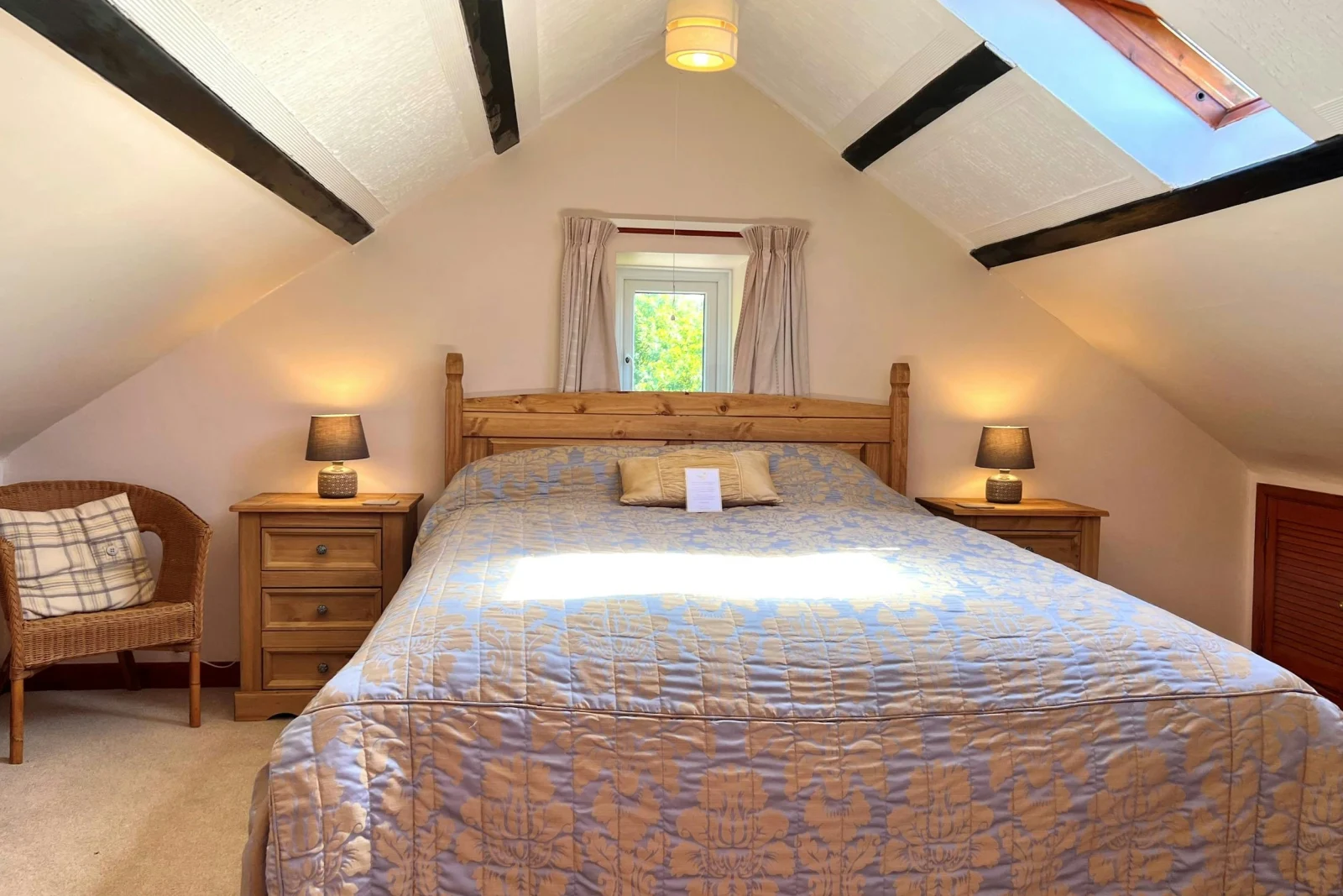 King-size bed, wicker chair, bedside cabinets and lamps with sloping ceilings