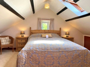 King-size bed, wicker chair, bedside cabinets and lamps with sloping ceilings