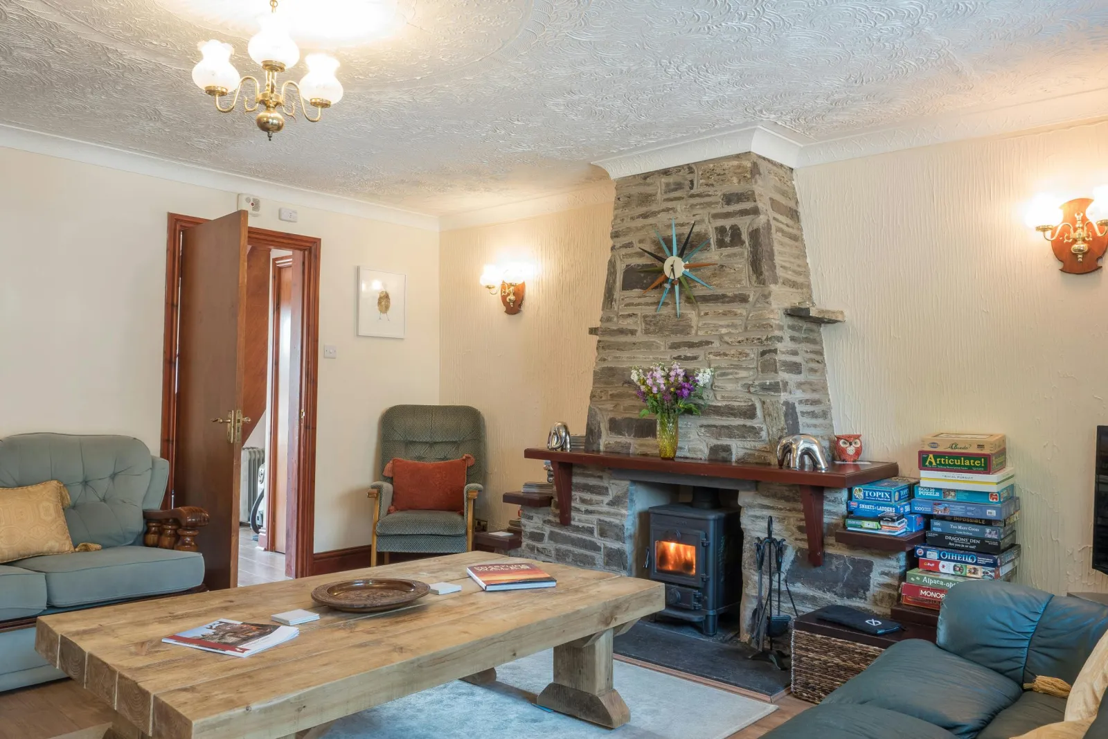 Stone fireplace with wood burner, coffee table and sofas and armchairs