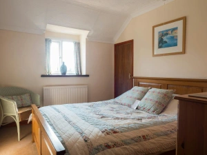 Double bed with quilted cover with a Lloyd Loom chair and chest of drawers