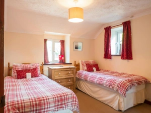 Twin single beds, chest of drawers with lamp and two windows