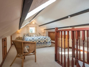 Attic double bed, cabinets with lamps, wicker chair and wooden bannister