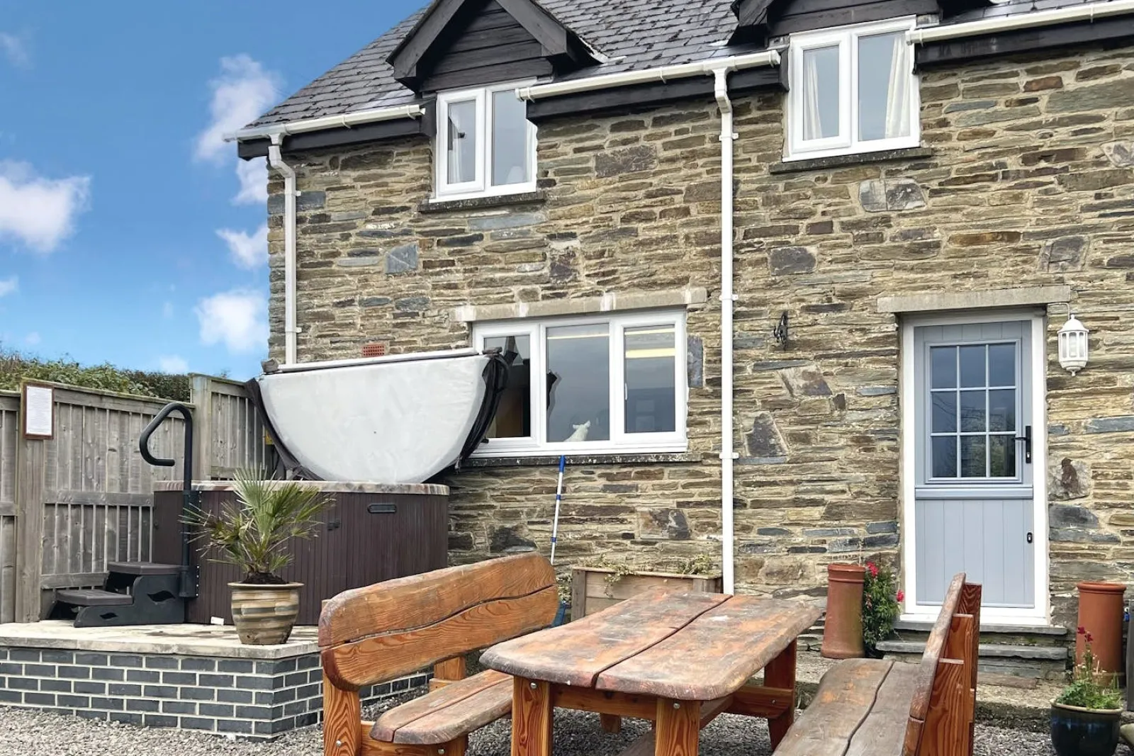 Oaktree Cottage from the garden, gravel area with table, seats and hot tub