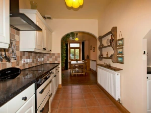 Fitted kitchen with cooker; leading to dining area with table and seven chairs