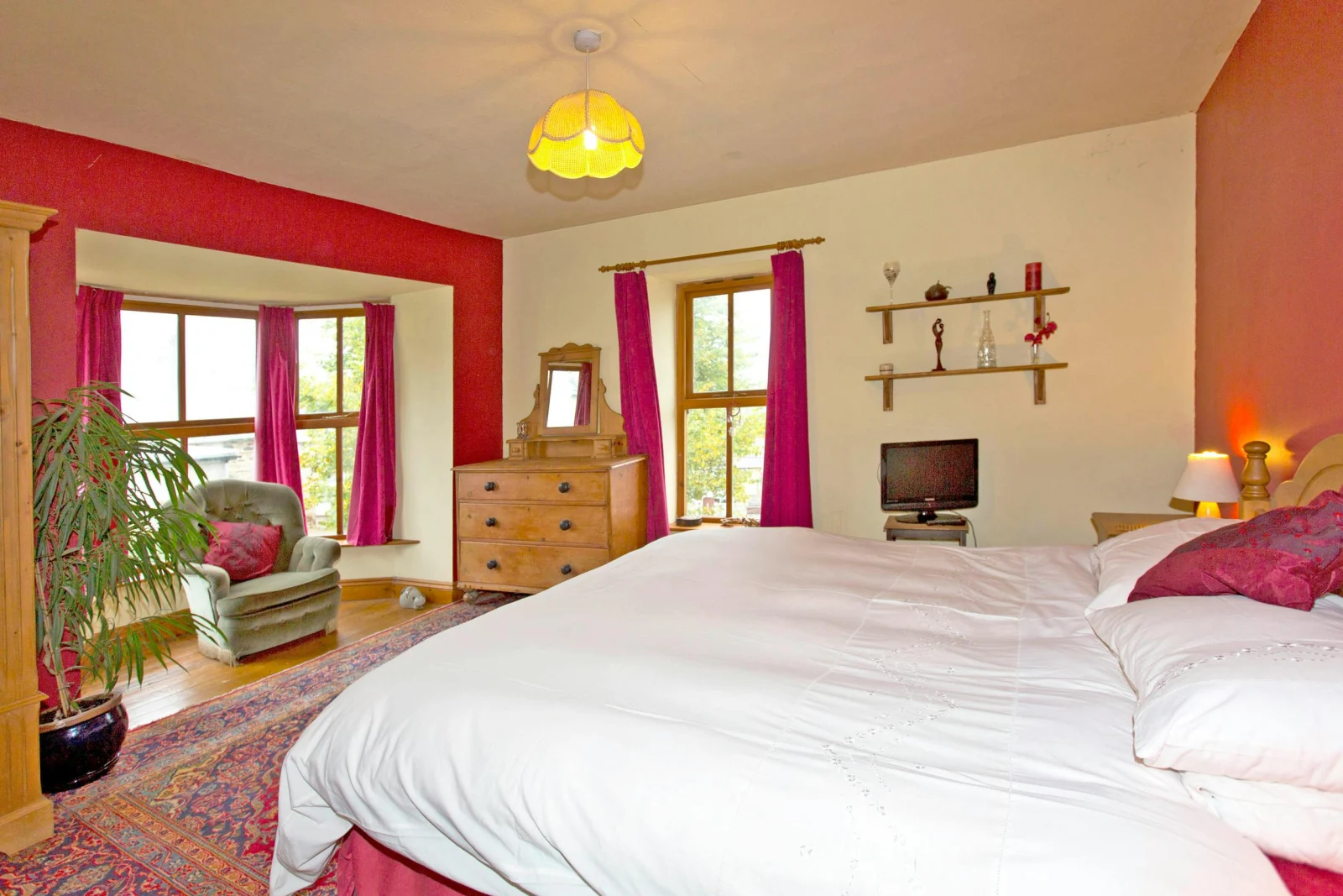 Bedroom with bay window: super king bed, chest of drawers with mirror, bedside cabinet with lamp, armchair and small TV
