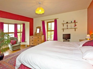 Bedroom with bay window: super king bed, chest of drawers with mirror, bedside cabinet with lamp, armchair and small TV