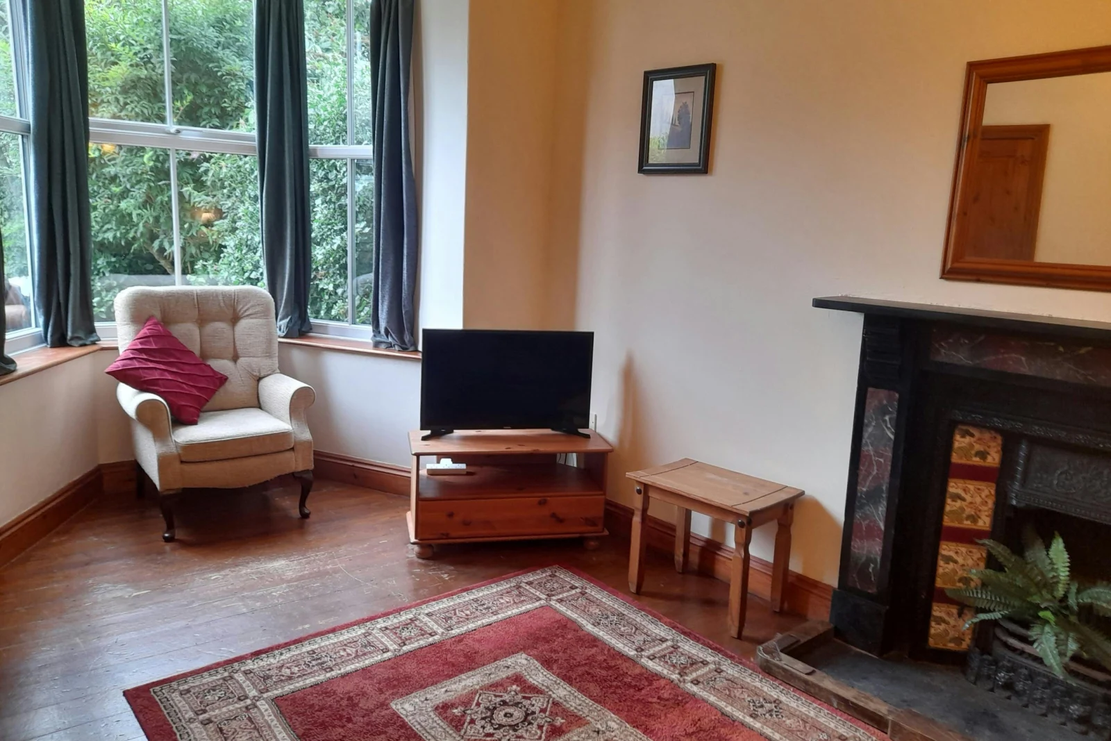Fireplace with mantlepiece, mirror above, small flat screen tv on unit and leather armchair