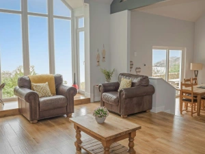 Lounge area with two armchairs and coffee table; dining area and breakfast bar