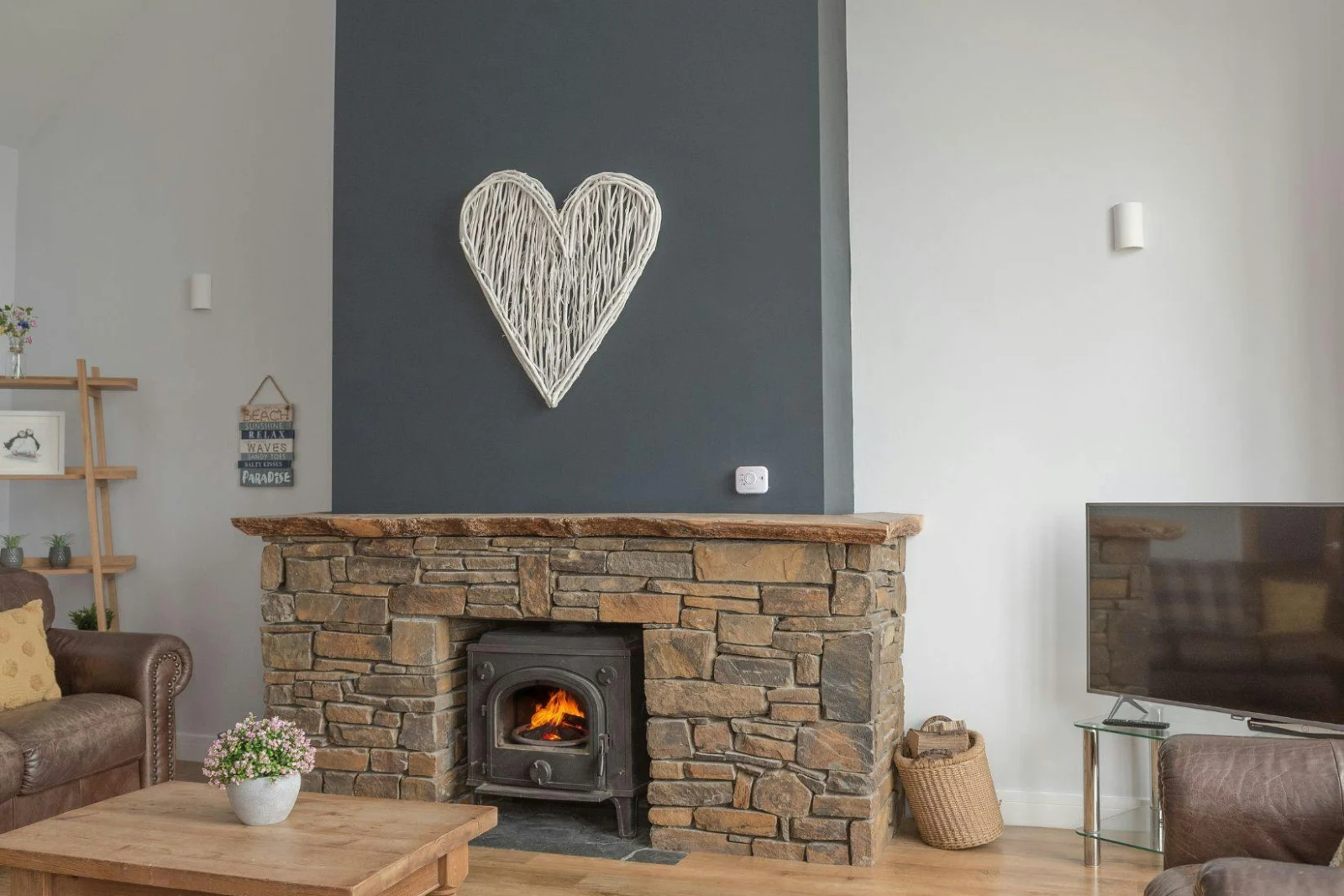 Living area with fireplace and log burner, TV on stand, armchair and coffee table