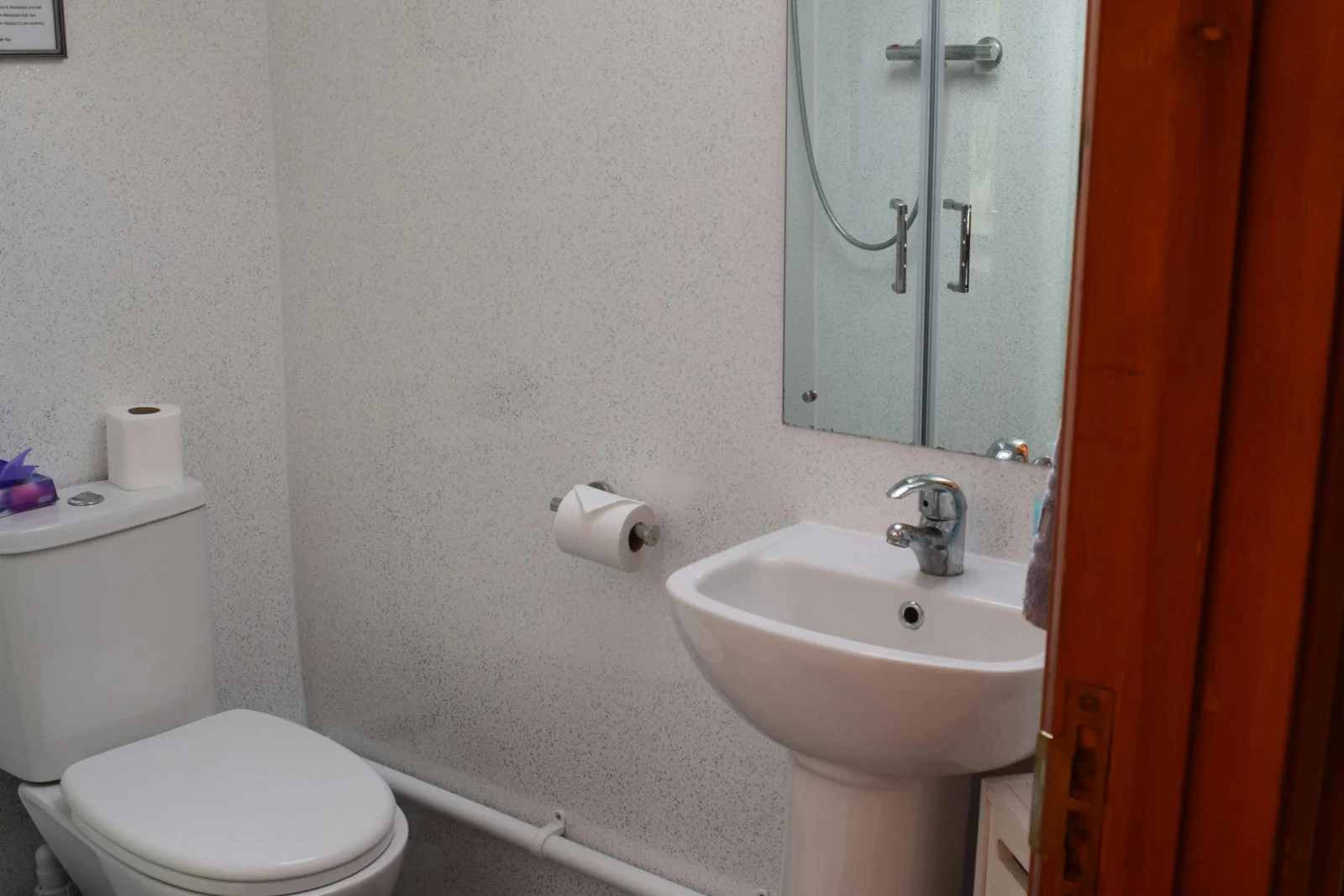 Shower room with wash basin with mirror above and toilet