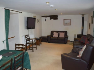 Sitting and dining room with log burner, sofas, armchair, dining table with chairs and wall mounted TV