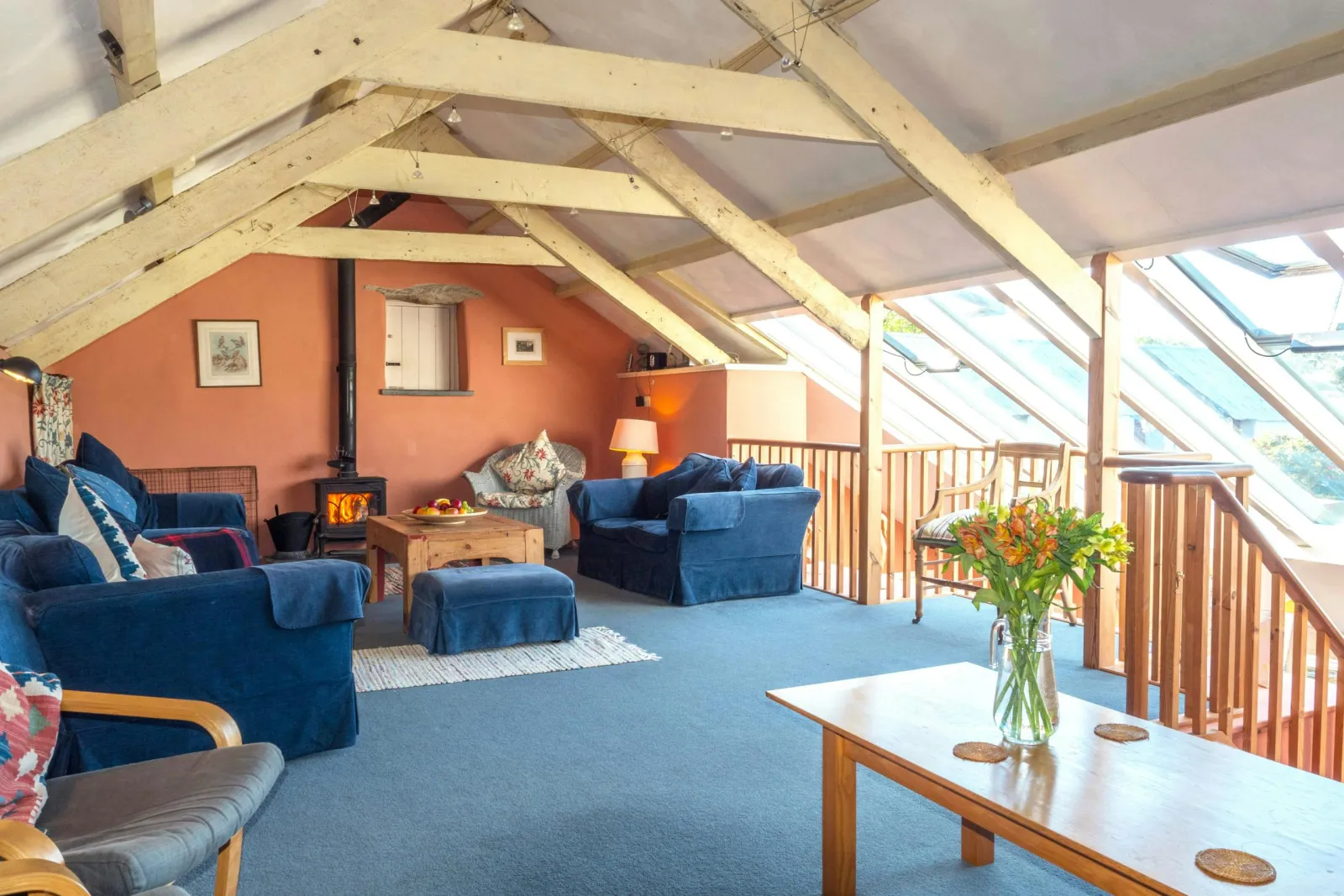 Living area with, sofas, log burner, armchair, beamed ceiling