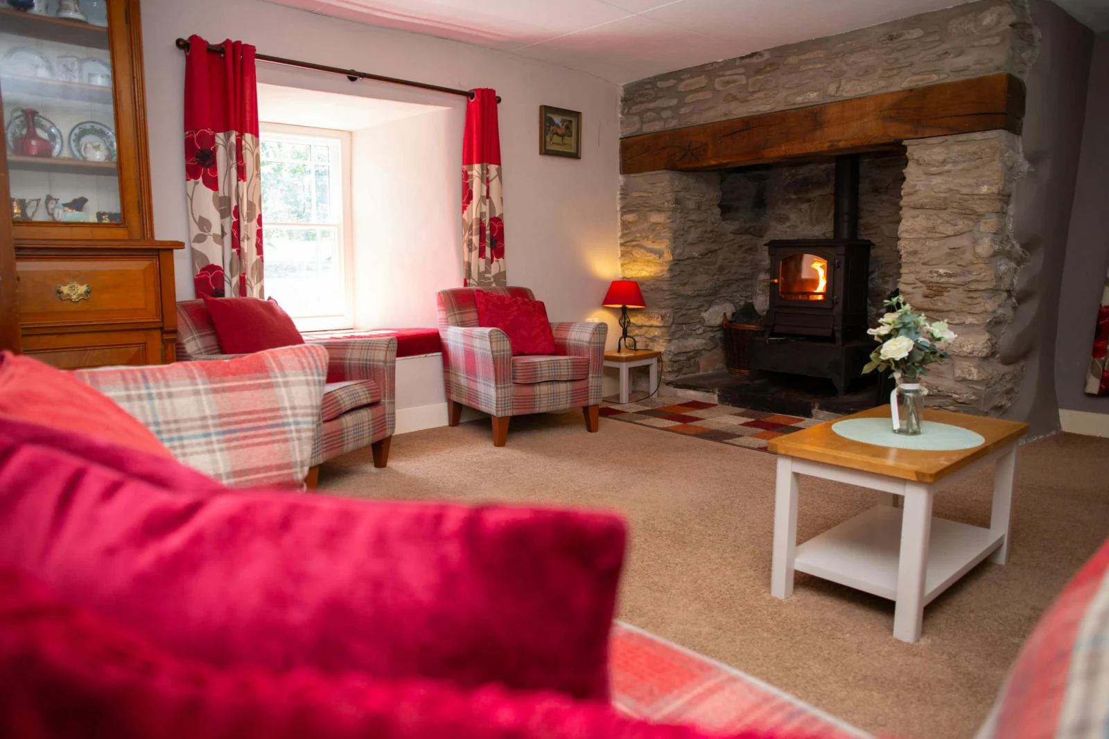 Sofa, armchairs, coffee table, corner table with lamp and wood burner in inglenook fire place