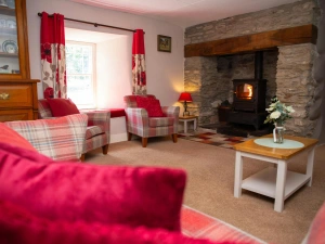 Sofa, armchairs, coffee table, corner table with lamp and wood burner in inglenook fire place