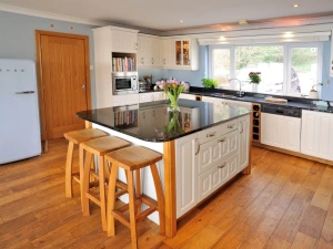 Island with bar stools in the centre of kitchen, Smeg fridge, dishwasher, toaster and built-in microwave