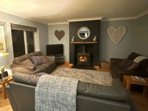 Three leather sofas with cushions, log fire, side tables with lamp, flat screen TV on shelving unit