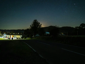 Night sky filled with stars and view of houses down the road lit up with street lights