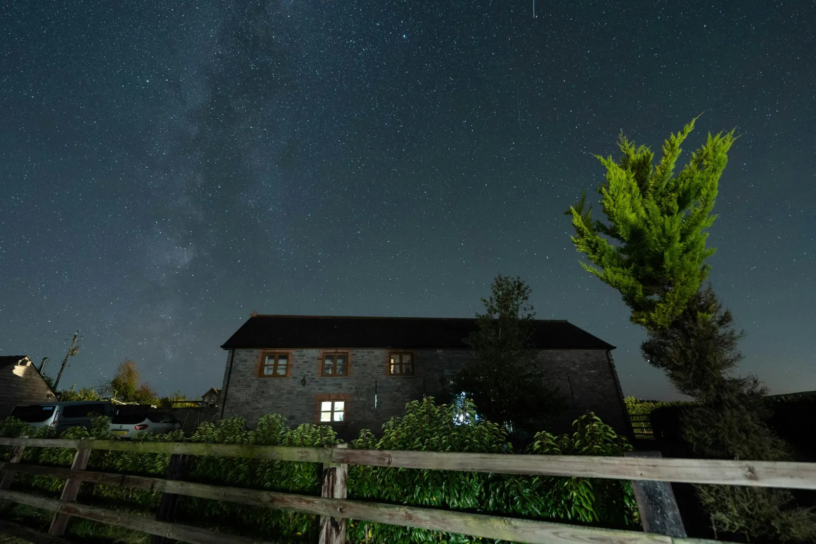 Outside of cottage at night with sky filled with stars.