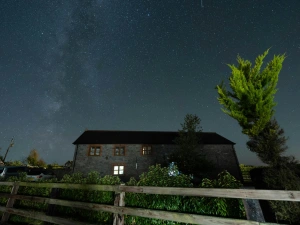 Outside of cottage at night with sky filled with stars.