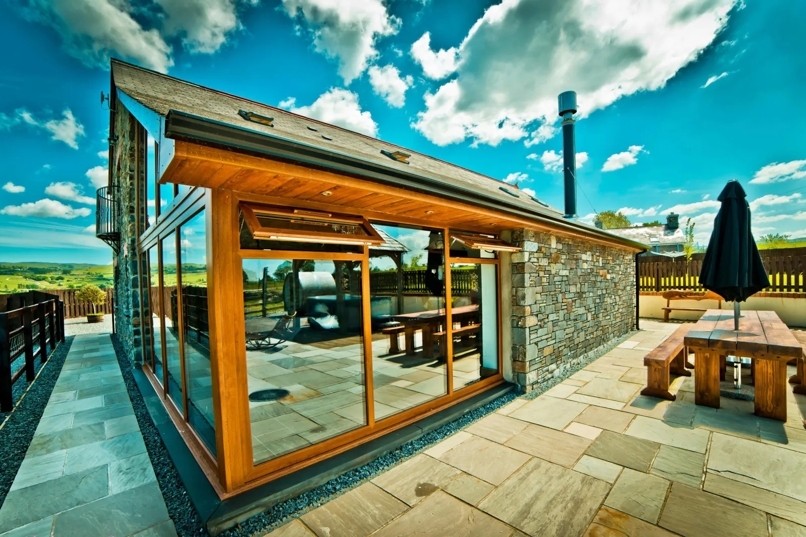 Llwyn Teifi and patio seating area with large table, benches and parasol