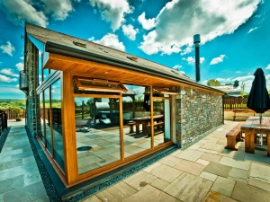 Llwyn Teifi and patio seating area with large table, benches and parasol