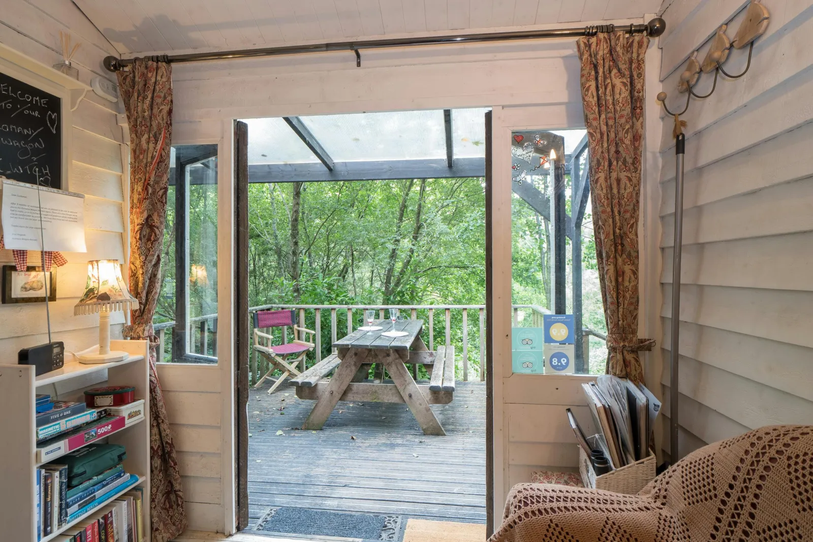 Seating area with sofa, book shelf, double doors to deck with picnic bench