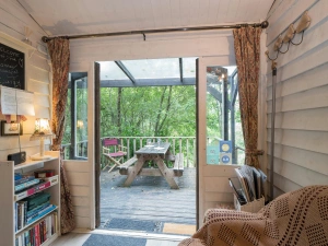 Seating area with sofa, book shelf, double doors to deck with picnic bench