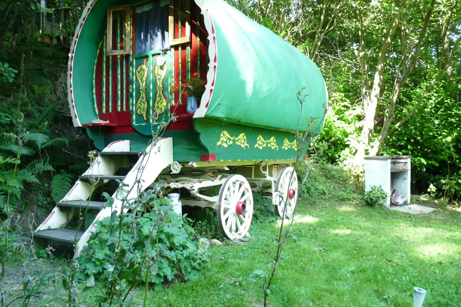 Romany Wagon Retreat surrounded by lawns and trees, barbecue