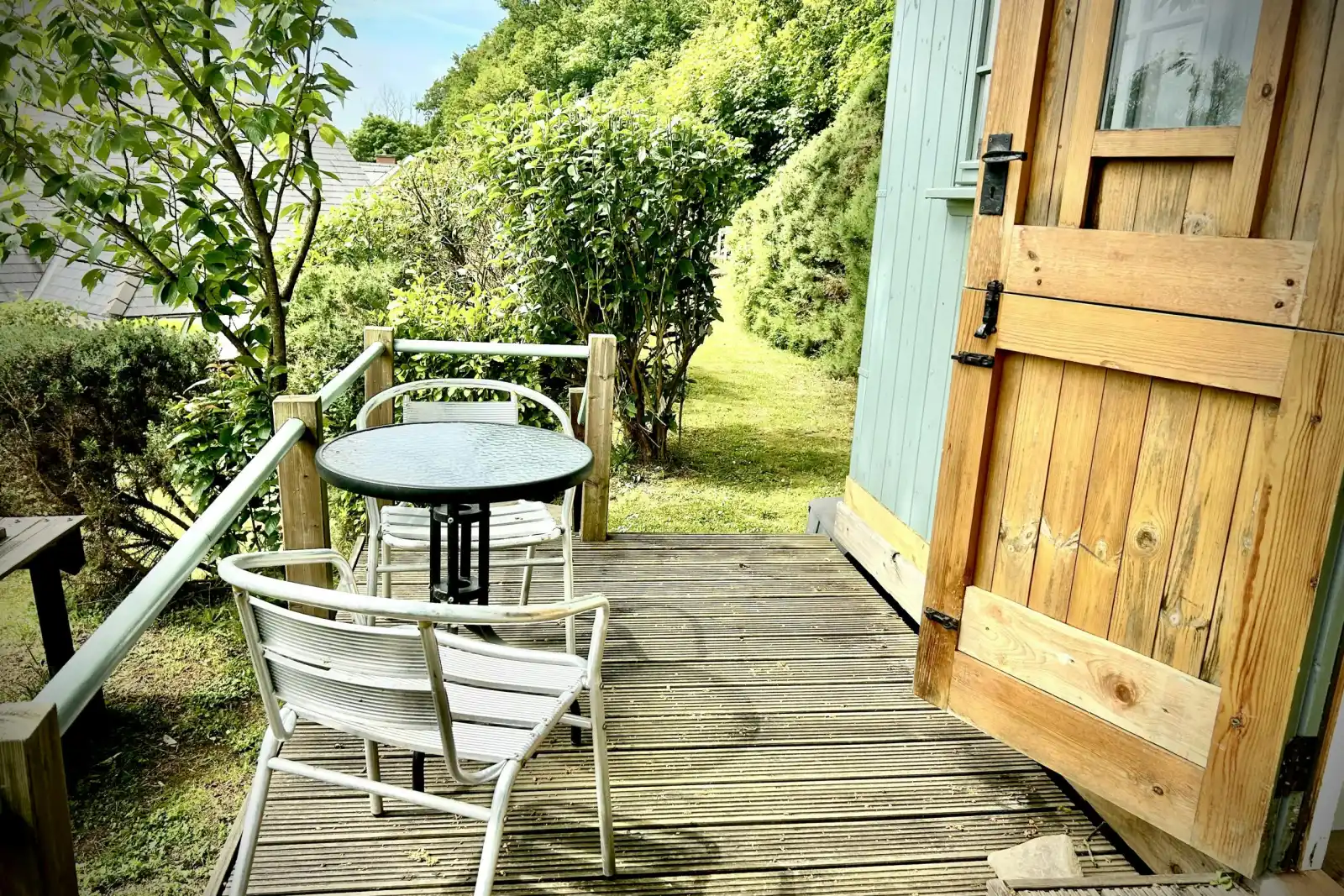 Wooden deck with round table and two chairs beside an open wooden door