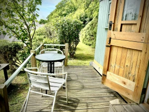 Wooden deck with round table and two chairs beside an open wooden door